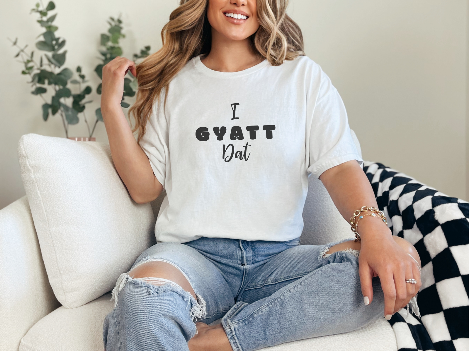 a woman sitting on a couch wearing a t - shirt that says i gyat