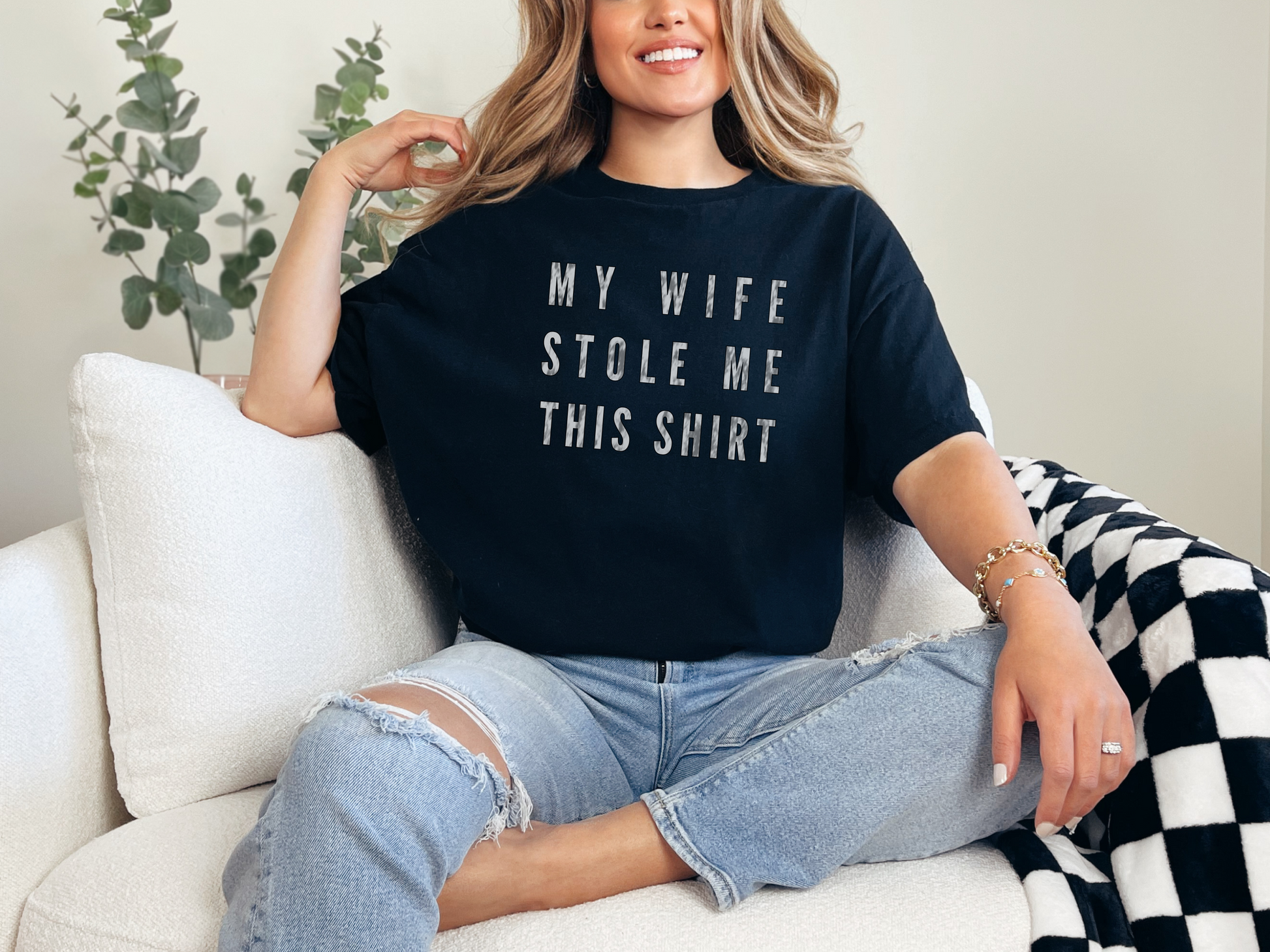 a woman sitting on a couch wearing a t - shirt that says my wife stole