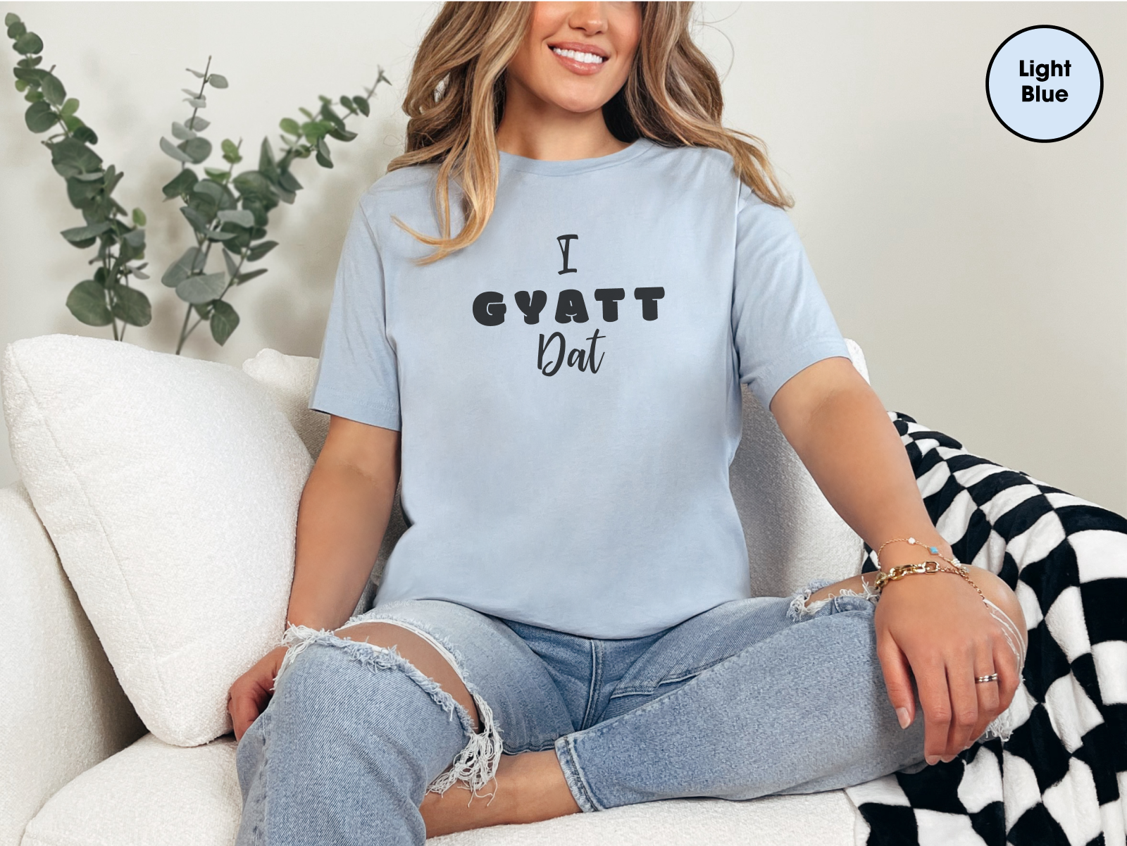 a woman sitting on a couch wearing a t - shirt that says i gyat