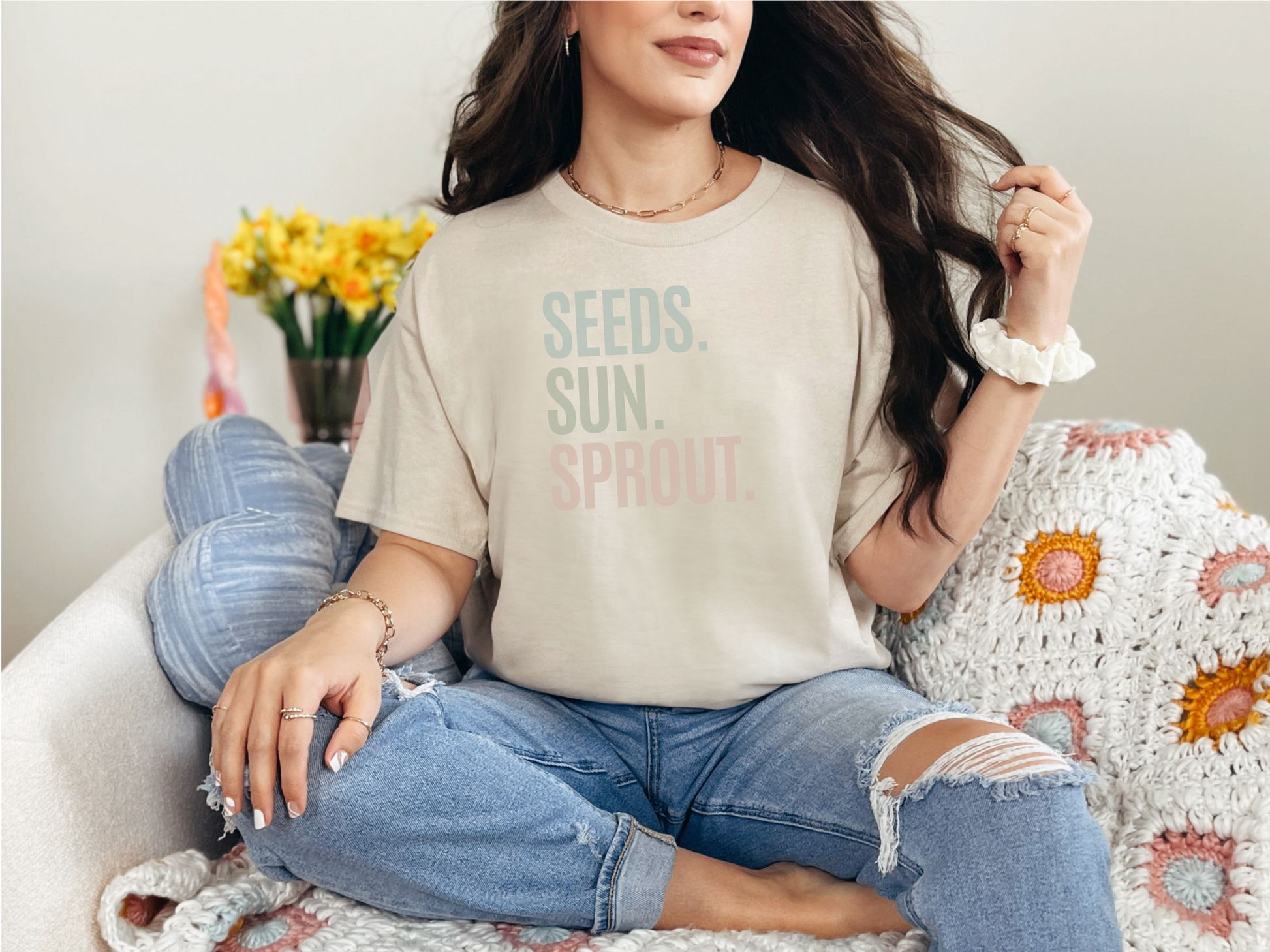 a woman sitting on a couch wearing a t - shirt that says seeds, sun