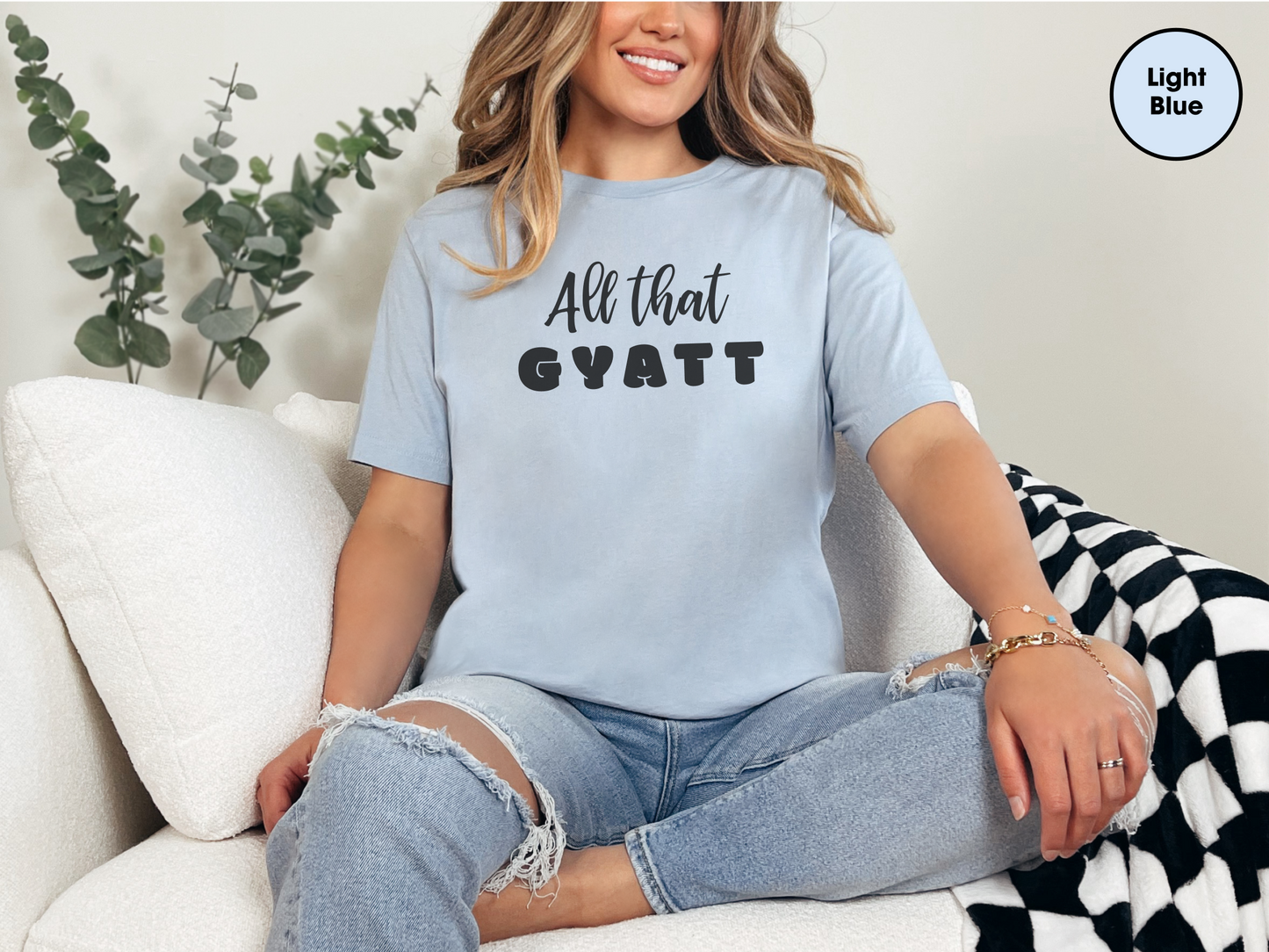 a woman sitting on a couch wearing a t - shirt that says all that g