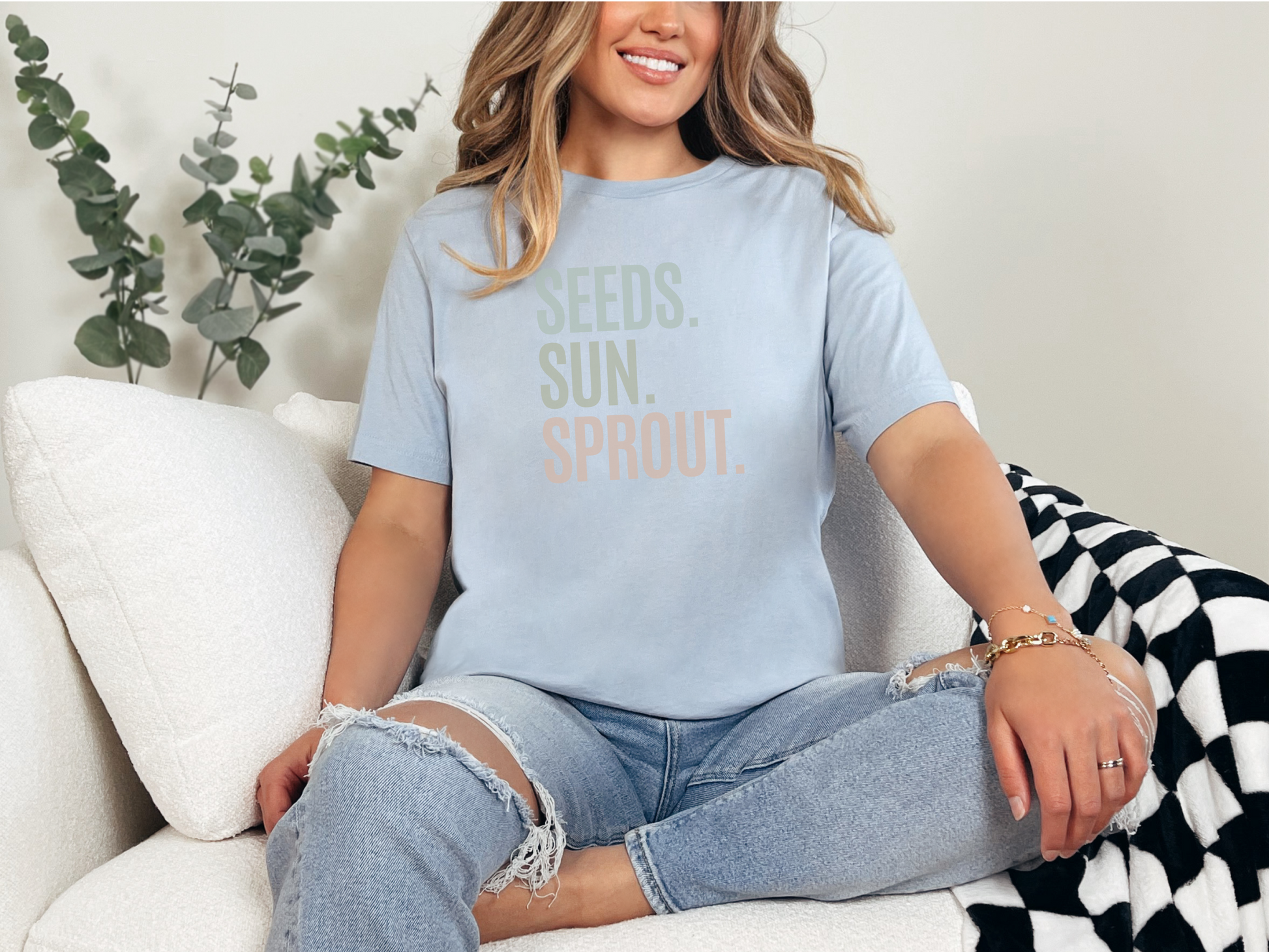 a woman sitting on a couch wearing a t - shirt that says seeds, sun