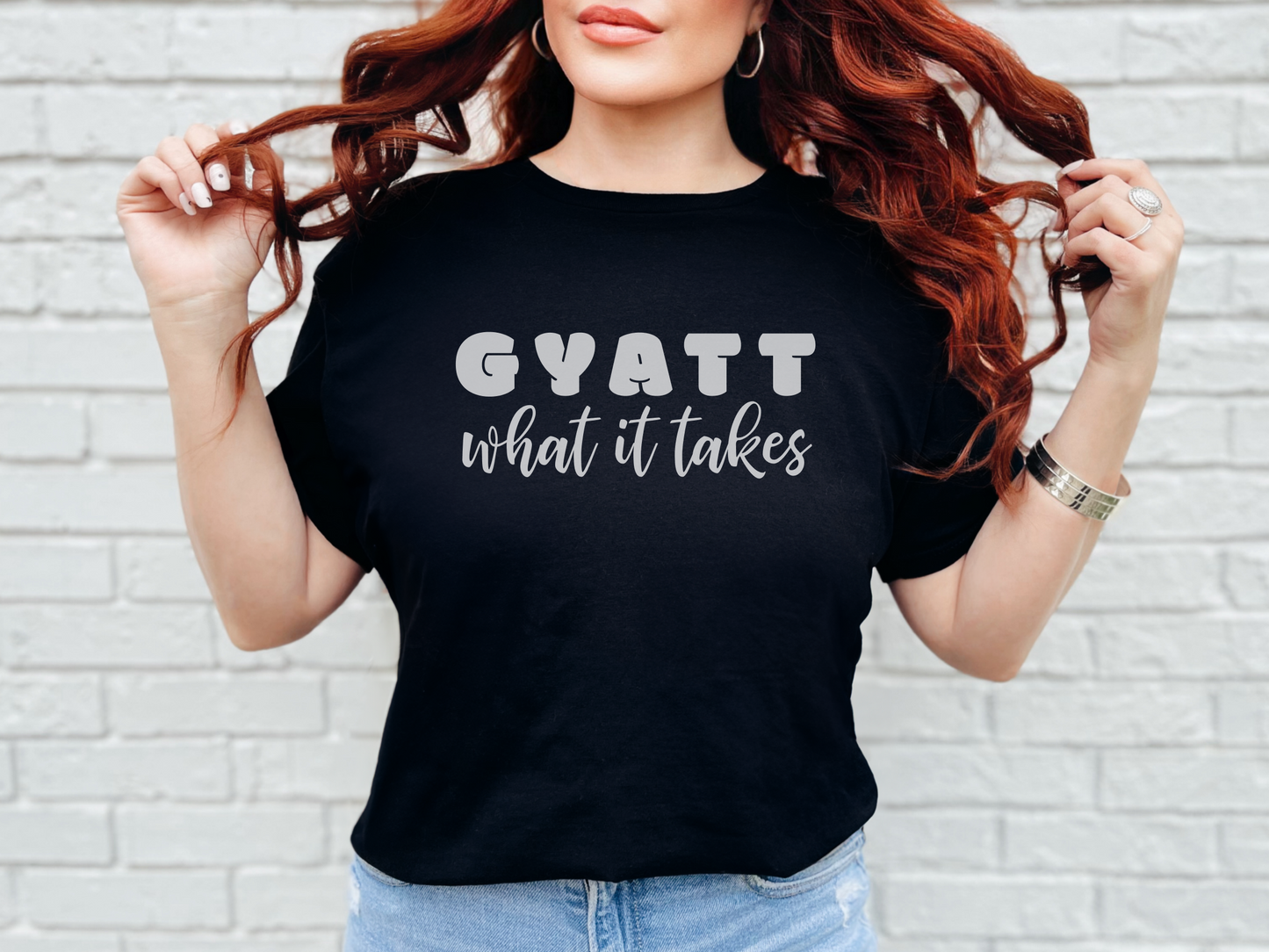 a woman wearing a black shirt that says gyatt what it takes