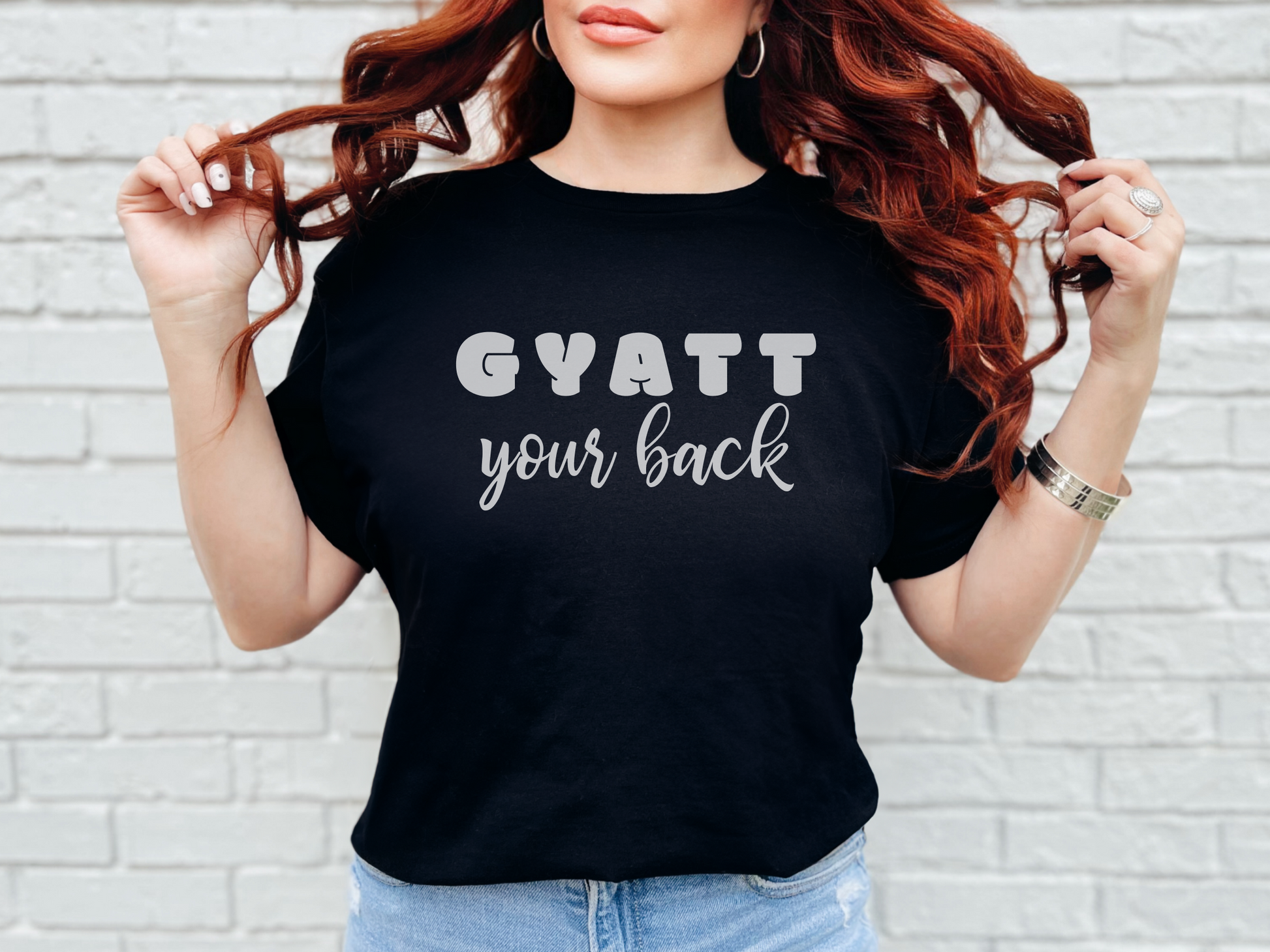 a woman with red hair wearing a black shirt that says gyatt your back