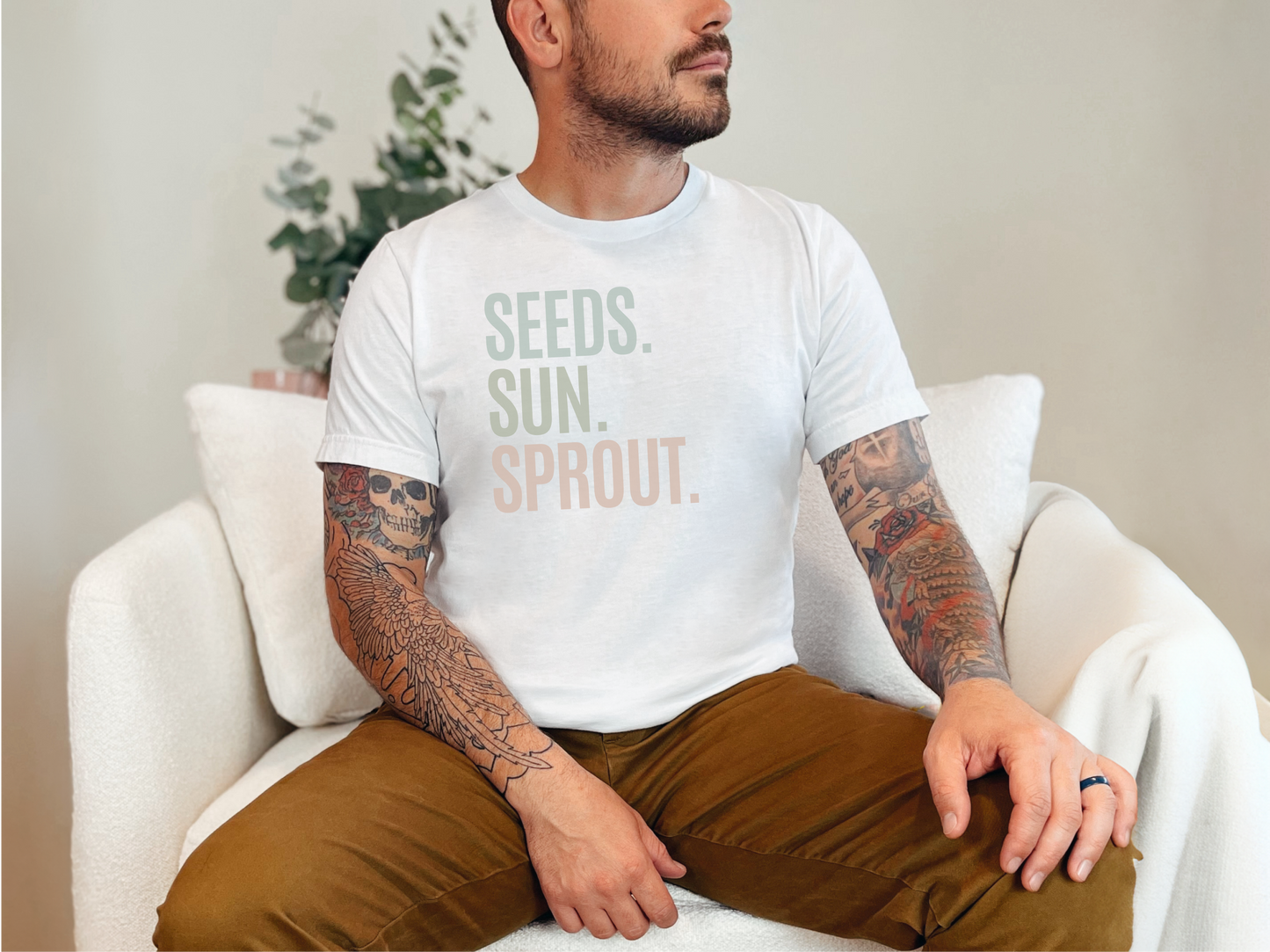 a man sitting on a white chair with a tattoo on his arm