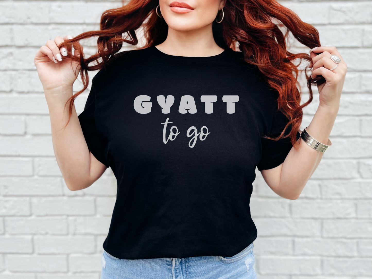 a woman with red hair wearing a black shirt that says gyatt to go