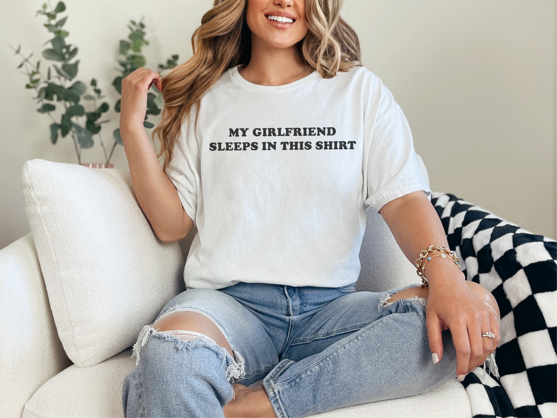 a woman sitting on a couch wearing a t - shirt that says, my girlfriend