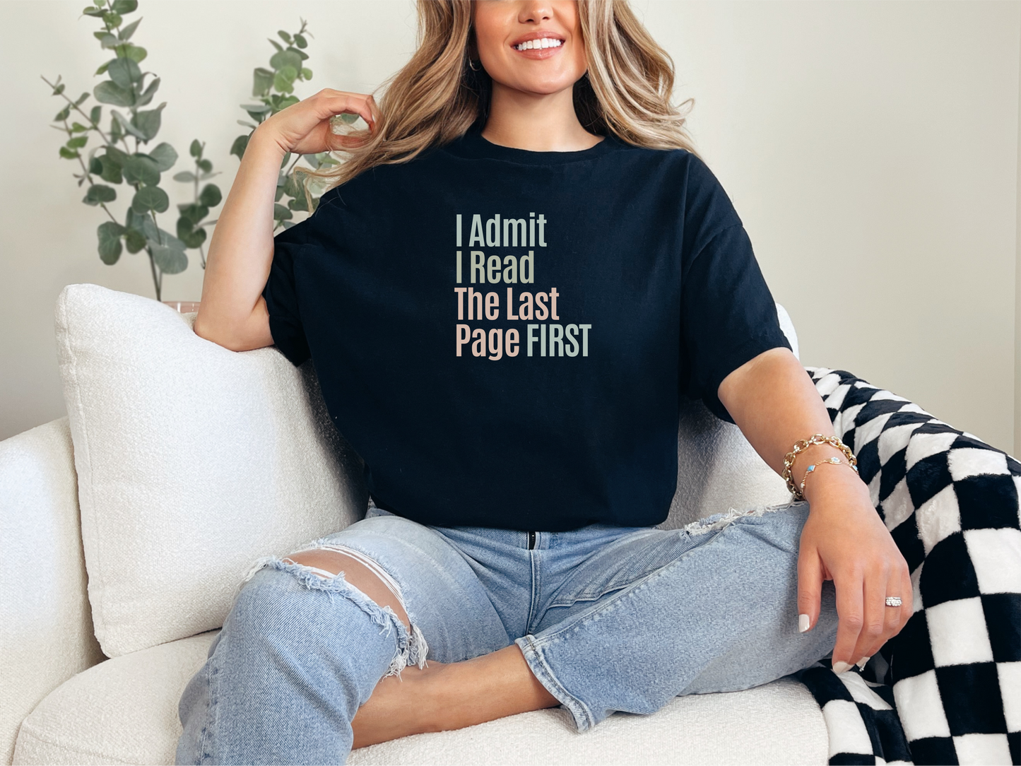 a woman sitting on a couch wearing a black t - shirt