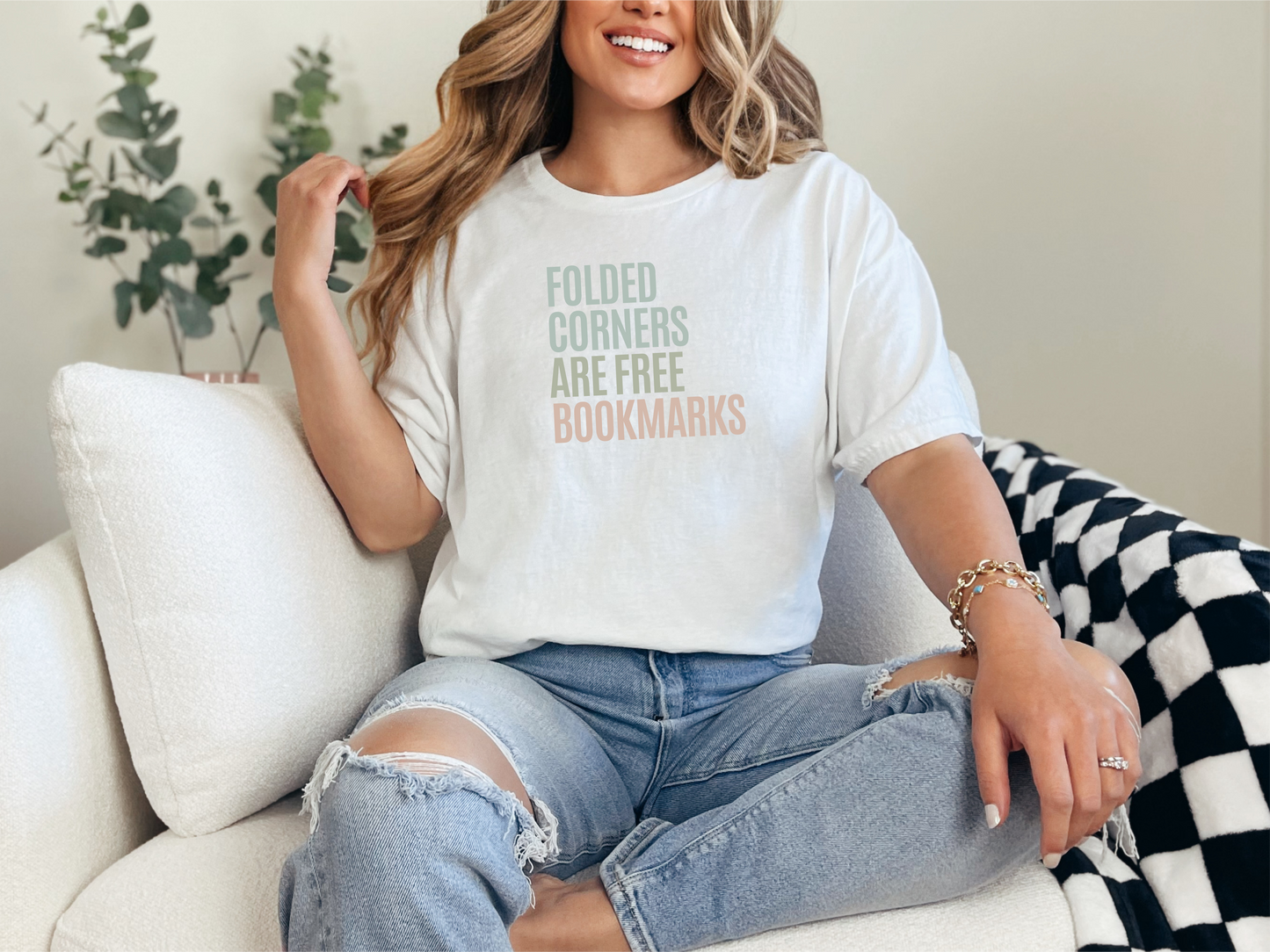 a woman sitting on a couch wearing a t - shirt that says folded corners are