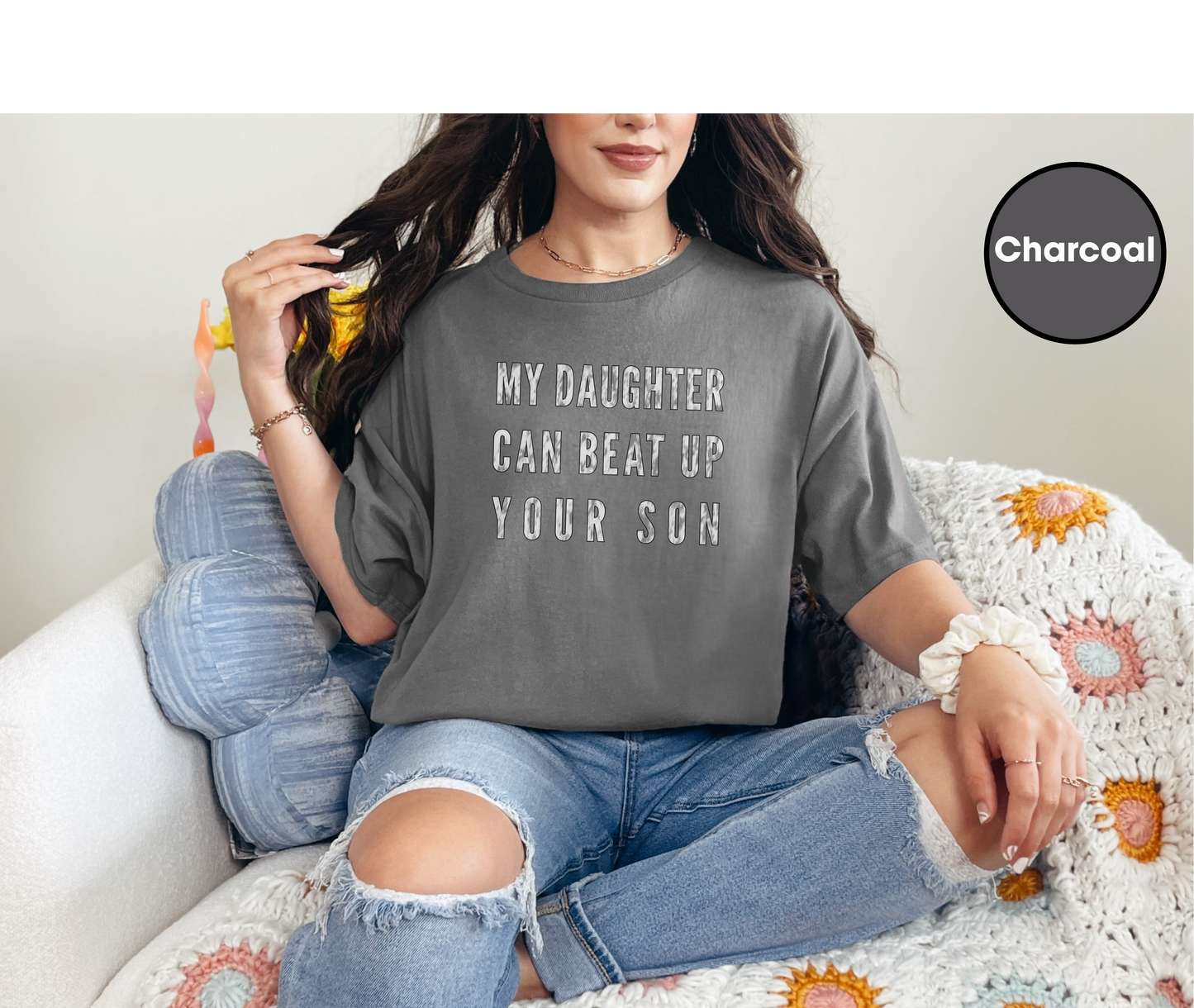 a woman sitting on a couch wearing a t - shirt that says, my daughter