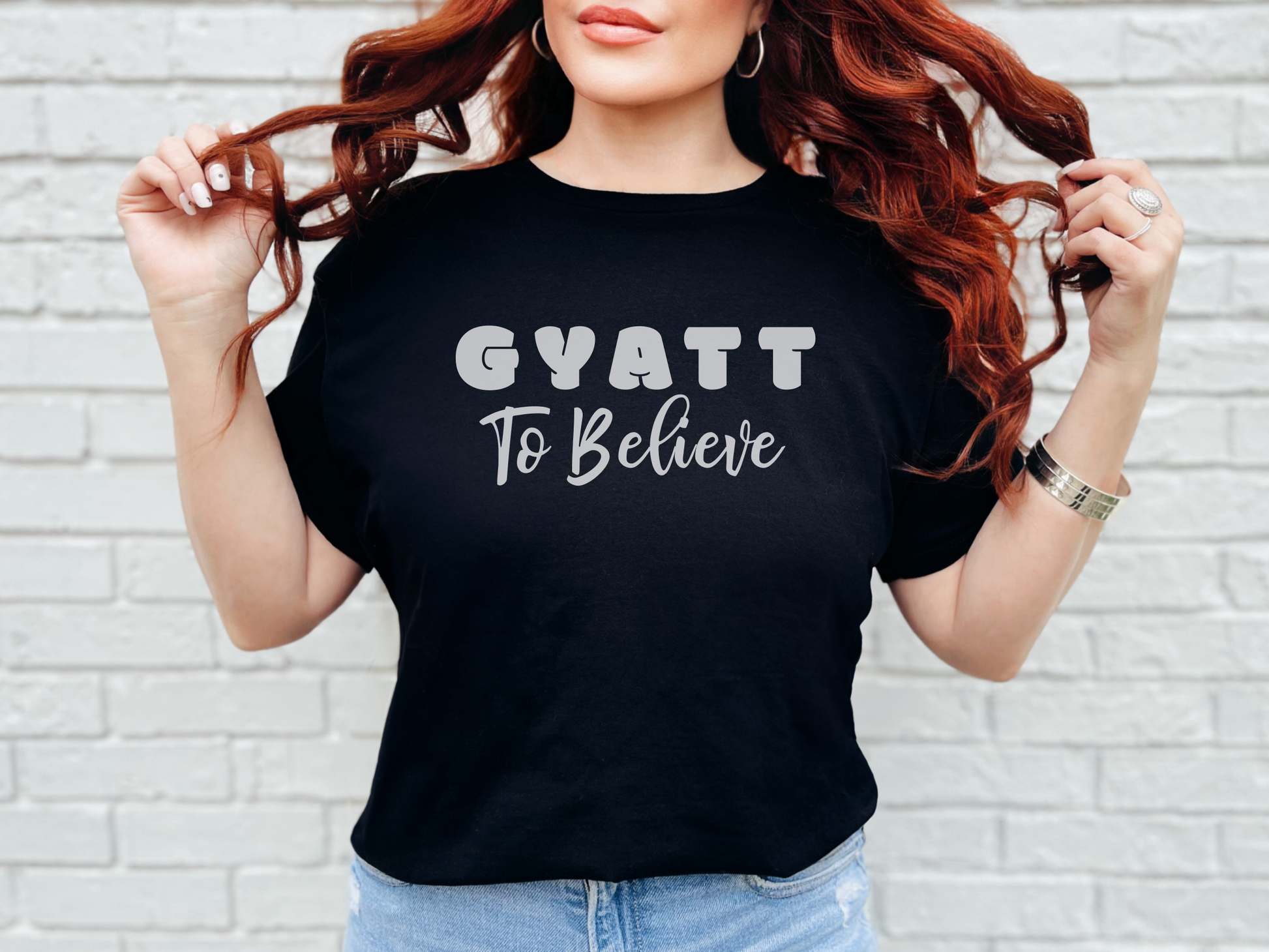 a woman wearing a black shirt that says gyatt to believe