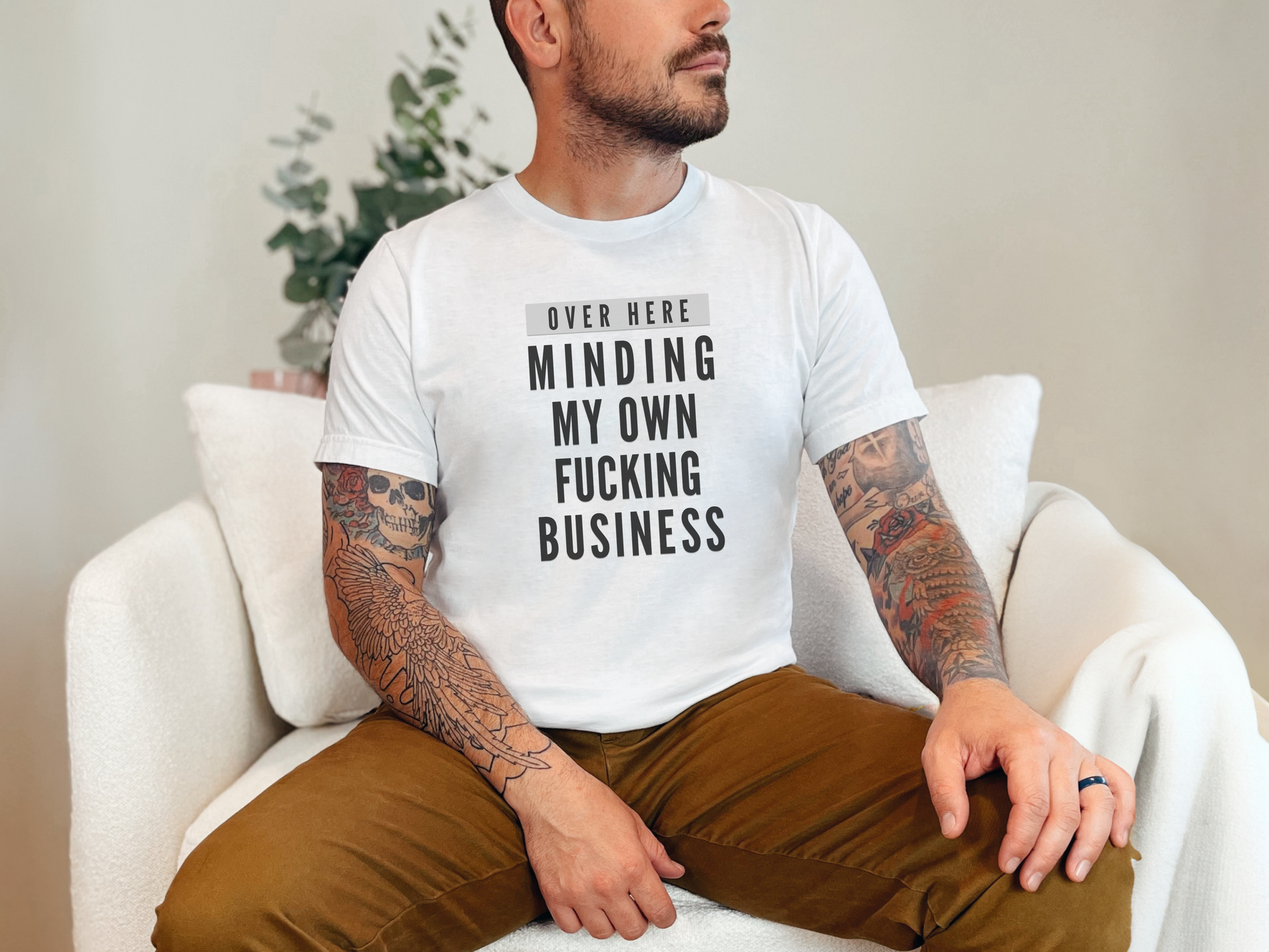 a man sitting on a white chair with a tattoo on his arm