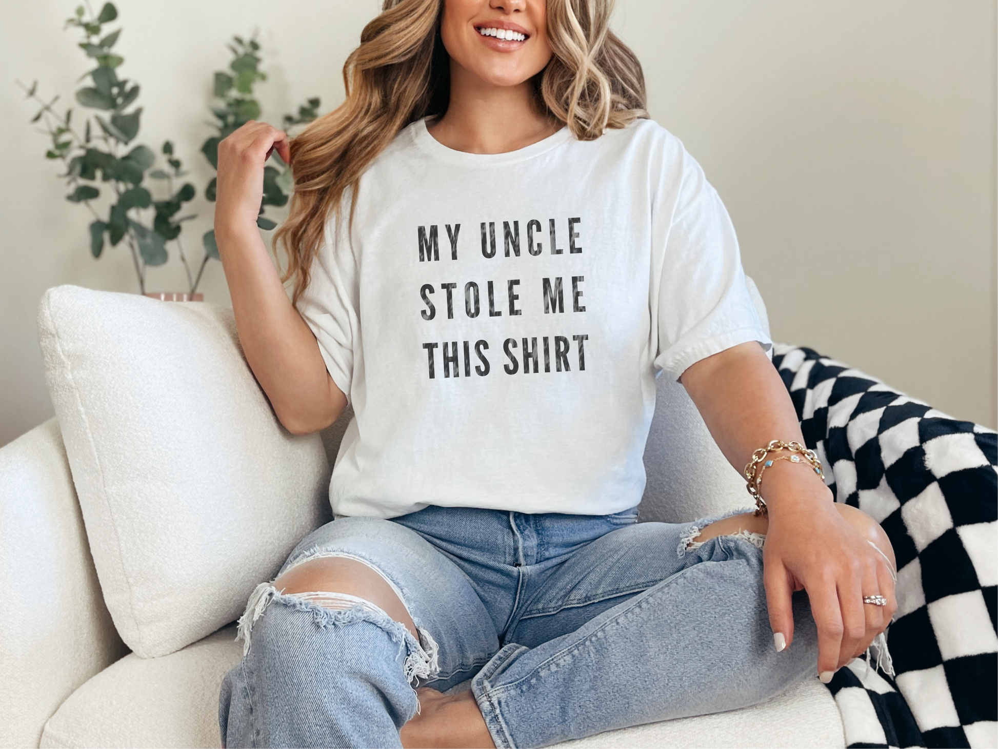 a woman sitting on a couch wearing a t - shirt that says, my uncle