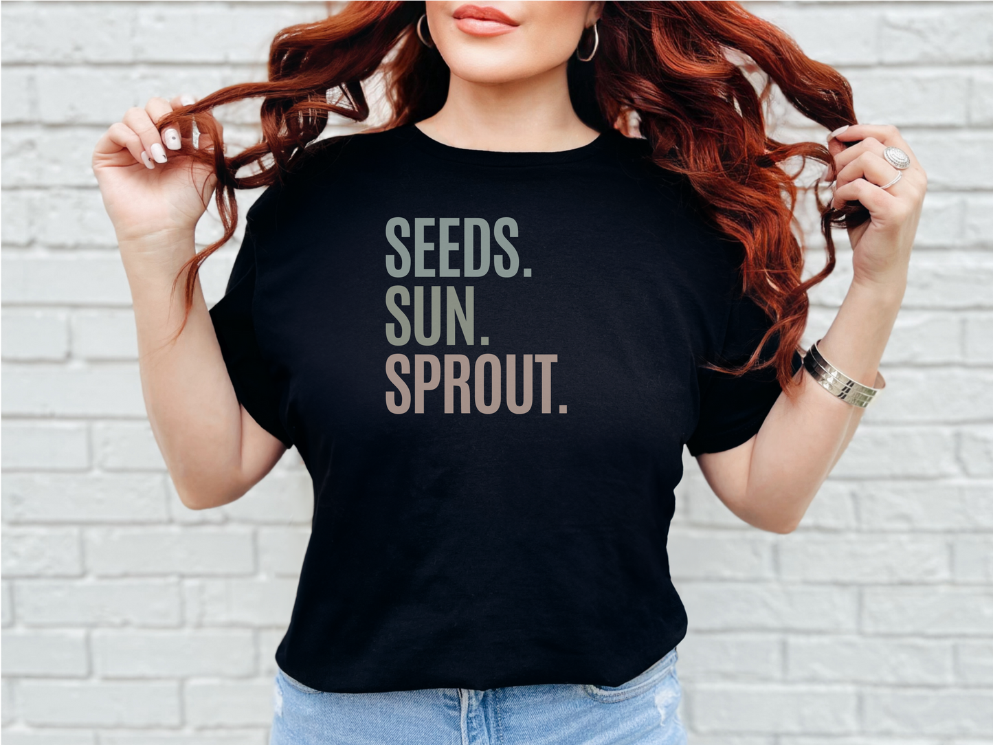 a woman with long red hair wearing a black shirt that says seeds, sun,